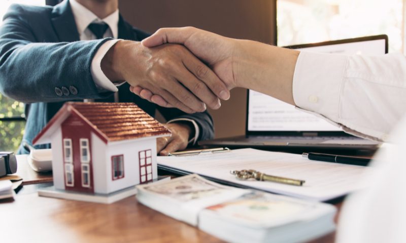 Real-estate agent shaking hands over contract and house model – negotiating luxury home purchases in Las Vegas