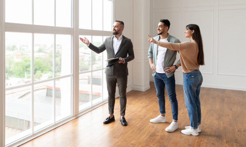 Young buyers touring floor-to-ceiling-window great room with their Las Vegas luxury Realtor